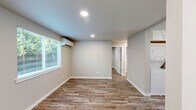 Located in Lacey, WA, this thoughtfully designed 2-bedroom, 1-bathroom unit makes excellent use of its compact footprint. Consistent wood-look plank flooring flows throughout every room, complemented by neutral gray and beige walls that create a clean, cohesive aesthetic.

The kitchen is a standout feature, outfitted with white shaker-style cabinetry, light quartz countertops, a stainless steel refrigerator, range, microwave, and dishwasher. A window above the sink brings in natural light and adds an open feel to the space.

Both bedrooms are well-proportioned, each featuring recessed lighting, wood-look flooring, and windows that overlook the surrounding greenery. The primary bedroom includes two doors — one leading to the hallway and one to a closet — providing practical storage. The second bedroom also benefits from natural light through a large window with a view of outdoor foliage.

The bathroom is finished with a clean, all-white tub and shower surround paired with brushed nickel fixtures, maintaining the modern and minimalist tone found throughout the unit.

Overall, this single-floor unit offers a functional, move-in-ready layout with modern finishes, making it a practical and attractive option in the Lacey area.