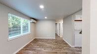 Located in Lacey, WA, this thoughtfully designed 2-bedroom, 1-bathroom unit makes excellent use of its compact footprint. Consistent wood-look plank flooring flows throughout every room, complemented by neutral gray and beige walls that create a clean, cohesive aesthetic.

The kitchen is a standout feature, outfitted with white shaker-style cabinetry, light quartz countertops, a stainless steel refrigerator, range, microwave, and dishwasher. A window above the sink brings in natural light and adds an open feel to the space.

Both bedrooms are well-proportioned, each featuring recessed lighting, wood-look flooring, and windows that overlook the surrounding greenery. The primary bedroom includes two doors — one leading to the hallway and one to a closet — providing practical storage. The second bedroom also benefits from natural light through a large window with a view of outdoor foliage.

The bathroom is finished with a clean, all-white tub and shower surround paired with brushed nickel fixtures, maintaining the modern and minimalist tone found throughout the unit.

Overall, this single-floor unit offers a functional, move-in-ready layout with modern finishes, making it a practical and attractive option in the Lacey area.