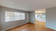 This well-appointed single-story unit offers two bedrooms and two bathrooms within a thoughtfully designed floor plan. The living area greets residents with warm wood-style flooring, neutral gray walls, and large windows fitted with horizontal blinds that allow ample natural light to filter through. A pendant light fixture illuminates the adjoining dining area, which connects seamlessly to the kitchen via a pass-through counter with built-in shelving.

The kitchen is equipped with light gray cabinetry, granite-style countertops, a stainless steel sink, and a stainless steel dishwasher, providing a clean and functional workspace. Both bedrooms feature plush carpeting, ceiling fans with integrated light fixtures, and generous closet space, including a walk-in closet in one bedroom. Sliding glass doors in one bedroom offer access to natural light and outdoor views. The bathrooms are finished with granite-topped vanities, light gray cabinetry, wood-style flooring, and a full tub-shower combination with tiled surround. Throughout the unit, textured ceilings and clean white baseboards contribute to a cohesive, move-in-ready aesthetic.