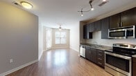 Located at 501 Willard St in Durham, NC, this single-floor residence offers a thoughtfully designed open-concept layout that seamlessly connects the living and kitchen areas. The kitchen is a standout feature, equipped with rich dark-espresso cabinetry extending to the ceiling, granite countertops, a subway tile backsplash, and a full suite of stainless steel appliances including a refrigerator, range, microwave, and dishwasher. Track lighting overhead adds a modern touch and ensures excellent task illumination throughout the space.

The open living area is finished with warm hardwood-style flooring that flows throughout the main living spaces, while neutral, warm-toned walls create a welcoming ambiance. A ceiling fan in the living area adds comfort, and large windows with blinds allow natural light to fill the room while offering outdoor views.

The bedroom features plush carpeting underfoot, a ceiling fan, a dedicated window for natural light, and access to a walk-in closet with built-in shelving — providing ample storage. The bathroom is finished with tile flooring and includes a full soaking tub and shower combination, a dark vanity, and a louvered linen closet nearby for additional storage convenience.