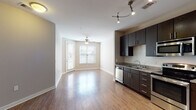 Located at 501 Willard St in Durham, NC, this single-floor residence offers a thoughtfully designed open-concept layout that seamlessly connects the living and kitchen areas. The kitchen is a standout feature, equipped with rich dark-espresso cabinetry extending to the ceiling, granite countertops, a subway tile backsplash, and a full suite of stainless steel appliances including a refrigerator, range, microwave, and dishwasher. Track lighting overhead adds a modern touch and ensures excellent task illumination throughout the space.

The open living area is finished with warm hardwood-style flooring that flows throughout the main living spaces, while neutral, warm-toned walls create a welcoming ambiance. A ceiling fan in the living area adds comfort, and large windows with blinds allow natural light to fill the room while offering outdoor views.

The bedroom features plush carpeting underfoot, a ceiling fan, a dedicated window for natural light, and access to a walk-in closet with built-in shelving — providing ample storage. The bathroom is finished with tile flooring and includes a full soaking tub and shower combination, a dark vanity, and a louvered linen closet nearby for additional storage convenience.