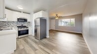 Located at 1032 S Normandie Ave in Los Angeles, this single-floor 2-bedroom, 2-bathroom unit offers a thoughtfully designed layout with modern finishes throughout. Light-toned vinyl plank flooring runs continuously across all rooms, lending a cohesive, clean aesthetic to the entire space.

The open-concept kitchen and living area form the heart of the unit. The kitchen features white shaker cabinetry, a mosaic tile backsplash, stainless steel appliances including a gas range and refrigerator, and ample counter space. The adjoining living area benefits from a front-facing window and ceiling fan, providing natural light and airflow.

The spacious primary bedroom includes a dedicated closet and access to a hallway, offering privacy and functionality. The second bedroom features a built-in closet with overhead storage, a wall-mounted air conditioning unit, and a window with vertical blinds. Both bedrooms display the same soft blue-gray wall tones and wood-look flooring.

Each bathroom is distinctly finished. One features a corner neo-angle glass shower enclosure with marble-style tile surround and a white vanity. The second bathroom includes a full tub-shower combo with sliding glass doors and matching marble-style tile, plus a window for natural light.