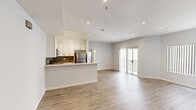 This thoughtfully designed 2-bedroom, 2-bathroom unit offers a cohesive single-floor layout that maximizes functionality and comfort. The open-concept living and kitchen area serves as the heart of the space, featuring light wood-tone luxury vinyl flooring that flows throughout. The kitchen is equipped with stainless steel appliances, including a gas range, built-in microwave, and refrigerator, complemented by crisp white shaker cabinetry, a stone mosaic tile backsplash, and a light-toned countertop with a double basin sink. A peninsula-style breakfast bar separates the kitchen from the living area, which is bathed in natural light and opens directly to a private balcony through sliding glass doors. Both bedrooms are generously proportioned, with the primary bedroom offering ample closet storage. Each bedroom features mirrored sliding closet doors, adding a sense of depth and brightness. The two bathrooms are finished with large-format gray marble-style tile surrounding the tub-shower combinations, paired with clean, neutral finishes. Recessed lighting throughout the unit maintains a bright and modern ambiance, while soft gray walls create a versatile, neutral backdrop. Hallways connect the living spaces to the bedrooms efficiently, contributing to an intuitive and well-organized floor plan.
