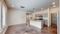 Located at 24 Bass Dr in Little Rock, Arkansas, this two-story home offers a modern aesthetic grounded in quality finishes throughout. The main level showcases polished stained concrete floors that flow seamlessly from the open-concept living and dining areas into the kitchen. The kitchen is a functional centerpiece, equipped with gray shaker-style cabinetry, granite countertops, a central island with a sink and pendant lighting, and a full suite of stainless steel appliances including a refrigerator, range, and over-the-range microwave. A walk-in pantry provides generous storage. The living area features ceiling fans and recessed lighting, with a staircase connecting to the upper level. The primary bathroom on the main level includes a dual-sink vanity with vessel bowls set on granite counters, polished concrete floors, a tiled shower surround, and direct access to a spacious walk-in closet with built-in shelving. Upstairs, bedrooms feature light wood-tone vinyl plank flooring, ceiling fans, and natural light from windows. A secondary bathroom offers a tub-shower combination with brushed nickel fixtures. A dedicated laundry room with upper gray cabinetry, built-in washer and dryer hookups, and a utility shelf rounds out the home's practical layout.
