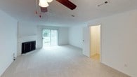 This two-story residence offers a practical and comfortable layout across both levels. The kitchen is designed for efficiency, featuring white cabinetry, a wood-toned backsplash, laminate countertops, a double stainless steel sink, and black appliances including a built-in microwave and electric range. Hardwood-style flooring and a window allowing natural light complete the space.

The living area is generously proportioned, showcasing light carpet, a wood-burning fireplace, exposed ceiling beam, and a ceiling fan. A sliding glass door opens to an outdoor area, flooding the room with natural light. An open sightline connects the living space to additional rooms, including the kitchen.

The bedrooms are carpeted and equipped with ceiling fans and natural light from windows. The primary bedroom stands out with multiple closets offering ample storage, while additional bedrooms provide similar comfort. A staircase is visible from the upper-level bedroom, indicating the two-floor layout.

The bathrooms are clean and functional, featuring light-toned tile flooring, vanities with generous countertop space, large mirrors with overhead lighting, and tiled shower surrounds. Throughout, the home maintains a neutral, light color palette with textured ceilings.