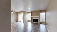 Located in Arlington, TX, this one-bedroom, one-bathroom apartment offers a practical and comfortable single-floor layout. The open living room is a standout, featuring rich wood-look flooring, a ceiling fan, and a tiled fireplace with a white mantle that serves as a natural focal point. Multiple windows fill the space with natural light, and sliding glass doors lead to a private balcony, extending the living area outdoors. The galley-style kitchen is efficiently designed with cream cabinetry, a subway tile backsplash, light stone countertops, and stainless steel appliances including a range and refrigerator. The textured ceilings carry throughout the unit, lending a consistent character to each room. The bedroom is a comfortable size, complete with a ceiling fan, a large sliding-door closet, and a window that allows in natural light. Wood-look flooring continues here, complementing the warm, neutral tones found throughout. The bathroom features a vanity with matching cabinetry and wood-look tile flooring. Throughout the unit, warm beige walls and consistent flooring create a cohesive, move-in-ready aesthetic well-suited for everyday living.