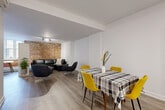 Located at 150 Rue King in Montréal's vibrant Griffintown neighbourhood, this well-appointed one-bedroom, two-bathroom unit blends modern finishes with industrial character. The open-concept main living area seamlessly connects the kitchen, dining room, and living room, creating a bright and functional space finished with light hardwood-style flooring throughout. The kitchen is a standout, featuring sleek white cabinetry, a peninsula with bar seating, white quartz countertops, stainless steel appliances including a built-in oven, microwave, and refrigerator, and a double undermount sink. The dining area flows naturally into the spacious living room, where an exposed red brick accent wall serves as a striking architectural focal point, adding warmth and historic character to the contemporary design. The bedroom offers a comfortable retreat, complemented by three closets — including a walk-in with built-in wire shelving — providing generous storage. The two bathrooms are finished in a clean, all-white palette; the main bathroom includes both a soaking tub and a glass-enclosed walk-in shower. Recessed and track lighting illuminate the space throughout, enhancing its modern, polished ambiance.