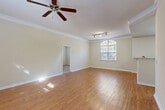 Located at 100 Ardsley Pl in Norcross, GA, this single-floor, one-bedroom, one-bathroom home offers a well-organized layout with a comfortable sense of space throughout. The open-concept living, dining, and kitchen area serves as the heart of the home, featuring warm wood-look hardwood flooring, crown molding, and a ceiling fan. A large arched window floods the living area with natural light and offers views of the surrounding greenery, while track lighting adds functional illumination. The galley-style kitchen is equipped with white cabinetry, ample counter space, a double-basin sink, a dishwasher, and a range, along with a window that brings in additional natural light. A separate pantry provides extra storage. The spacious primary bedroom is finished with plush carpet, multiple windows, and direct access to a walk-in closet featuring built-in wire shelving. A dedicated laundry area and utility room with an electrical panel add convenience. Three closets throughout the home ensure generous storage. The entrance welcomes with tiled flooring, while the overall neutral color palette and clean finishes create a bright, move-in-ready atmosphere throughout the home.