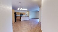 Located at 8200 W 20th St in Greeley, Colorado, this single-floor residence offers a well-designed, open-concept layout that seamlessly connects the kitchen and living areas. The kitchen is a functional centerpiece, featuring warm light oak cabinetry extending to the ceiling, dark granite-style countertops, a full suite of black appliances including a refrigerator with ice maker, electric range, and over-the-range microwave, as well as a central island with a sink that doubles as an informal breakfast bar. A pendant chandelier adds a finishing touch over the island. Hardwood-style flooring runs throughout the kitchen and open living area, which is accented by a ceiling fan and large sliding glass doors that lead to a private balcony with outdoor views. The bedrooms are carpeted for comfort, with one featuring a generous window that fills the room with natural light and neighborhood views. The bathrooms are consistent in design, each offering light oak vanities, dark countertops, large mirrors, and a shower-tub combination. Tile flooring is found in one bathroom, while the other continues the hardwood-style flooring from the main living area. The overall aesthetic is clean, neutral, and move-in ready.