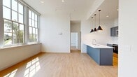 Located at 4231 River St in Willoughby, Ohio, this thoughtfully designed one-bedroom, one-bathroom unit offers a bright and modern living experience. The open-concept living area is characterized by soaring ceilings, light-toned hardwood flooring, and oversized grid-pane windows that flood the space with abundant natural light while framing pleasant outdoor views of the surrounding neighborhood.

The kitchen is a standout feature, showcasing gray shaker-style cabinetry extending to the ceiling, white quartz countertops, a classic subway tile backsplash, and a full suite of stainless steel appliances including a refrigerator, electric range, and built-in microwave. A blue kitchen island with pendant lighting adds a contemporary design accent and provides additional workspace and seating.

The bedroom is a well-proportioned, sun-filled retreat with large multi-pane windows and a ceiling fan, creating a comfortable and airy environment. A dedicated closet provides practical storage.

The bathroom is elegantly finished with penny round tile flooring, teal vertical subway tile accents, a gray vanity with an undermount sink, a round mirror, and a glass-enclosed walk-in shower. A hallway connects the rooms efficiently, completing the functional layout of this well-appointed Willoughby residence.