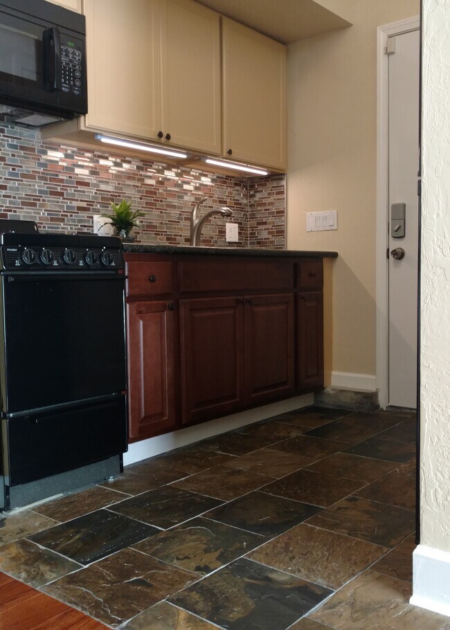 Kitchen with granite countertop, microwave, gas stove, fridge and small pantry loaded with appliances and kitchenware. - 2852 Betsy Way