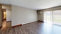 Located at 612 James Ave in Mankato, MN, this single-floor, 2-bedroom, 1-bathroom unit offers a practical and straightforward layout. The living area features durable hardwood-style flooring, baseboard heating, a textured ceiling, and a window with outdoor views that brings in natural light — a window unit air conditioner ensures year-round comfort. The kitchen is equipped with wood cabinetry, a coil-top electric range with an overhead exhaust hood, and ample counter space for meal preparation. A central hallway connects the main living spaces, finished with the same hardwood-style flooring and warm wood-trimmed doorways. Both bedrooms are carpeted for comfort and each features an open closet with a full-width hanging rod, providing generous storage. The primary bedroom is notably spacious, offering room for substantial furnishings. The bathroom includes a single-sink vanity with wood cabinetry, a mirrored medicine cabinet, a full tub-and-shower combination, and consistent hardwood-style flooring. Throughout the unit, neutral gray walls and warm wood trim create a cohesive and understated aesthetic suited to a variety of décor styles.