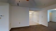 Located at 1900 Cardinal Trail Dr in Galloway, Ohio, this single-story home offers a straightforward and functional layout designed for comfortable everyday living. The interior features neutral white walls and clean baseboards throughout, creating a bright and cohesive aesthetic that is easy to personalize. The main living area is finished with plush wall-to-wall carpeting in a warm brown tone, providing a cozy underfoot feel. A ceiling fan overhead adds practical comfort to the space. The living area flows openly into an adjacent dining or secondary living space, separated by a partial wall that maintains an open and connected feel. The adjoining room is finished with hard flooring and is illuminated by a classic chandelier, lending a touch of elegance to the transition area. Flush-mount vents integrated into the walls ensure consistent climate control throughout the home. The consistent use of neutral tones and clean lines across both spaces gives the home a unified and move-in-ready appearance. Situated in the Galloway community of central Ohio, this property presents a solid foundation for those seeking a comfortable and accessible single-level living experience.