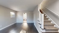 Located at 181 Derrer Rd in Columbus, Ohio, this multi-story home offers a practical and well-organized layout spread across three floors, including a basement. The main level welcomes you with a spacious living room featuring dark hardwood-style flooring, soft neutral gray walls, and a carpeted staircase with white balusters leading to the upper level. Natural light filters in through multiple windows fitted with blinds throughout the home. The kitchen is outfitted with gray shaker-style cabinetry, dark countertops, wood-look flooring, and a white range, creating a clean, functional cooking space. Two bedrooms provide comfortable accommodations; the primary bedroom benefits from dual windows and a ceiling fan, while the second bedroom is also well-lit with natural light. Both rooms carry the home's consistent hardwood-style flooring and neutral color palette. The full bathroom features a tub-shower combination, a white vanity with sink, and wood-look flooring. The basement level offers an open, unfinished space with painted concrete block walls, a painted floor, and exposed utility systems, presenting versatile potential for storage or future use. Two closets add to the home's practical storage options throughout.