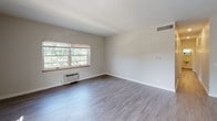 Located at 500 Fulton St E in Grand Rapids, Michigan, this single-floor unit offers a clean, functional layout designed for comfortable everyday living. The open living area is finished with smooth hardwood-style flooring and features a ceiling fan with light fixture, creating a bright and airy atmosphere. Large windows invite natural light throughout, with views of surrounding greenery adding a sense of calm to the interior.

The galley-style kitchen is efficiently designed with white cabinetry, dark countertops, stainless steel appliances including a microwave and dishwasher, and a double-basin sink with a modern faucet. Hardwood-style flooring continues seamlessly from the living space into the kitchen area.

The bedrooms are finished with wall-to-wall carpet and each features a window with blinds, offering natural light and a quiet, comfortable feel. One bedroom includes a wall-mounted climate control unit for individualized comfort.

Two bathrooms serve the unit — one features classic mosaic tile flooring with black accent details, a pedestal-style sink, and a mirrored medicine cabinet, while the second offers a vanity with dark countertop, white subway tile wainscoting, and a mirrored cabinet above. The neutral color palette throughout creates a cohesive and move-in ready environment.