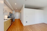 Located in Redmond, WA, this thoughtfully designed one-bedroom, one-bathroom unit offers a clean, modern aesthetic throughout. Warm hardwood-style flooring flows continuously across the entire space, complementing the bright white walls and recessed lighting that create a fresh, contemporary atmosphere.

The open-concept kitchen and living area form the heart of the unit. The kitchen is well-appointed with a full suite of stainless steel appliances — including a refrigerator, electric range, over-the-range microwave, and dishwasher — paired with white upper cabinetry, warm wood-toned lower cabinets, white quartz countertops, and a classic subway tile backsplash. A single-basin stainless steel sink completes the functional layout.

The living area is open and airy, benefiting from large windows fitted with horizontal blinds that allow for natural light control. The bedroom is a comfortable, well-proportioned space featuring oversized windows with views of the surrounding Redmond neighborhood, filling the room with natural light. Three closets throughout the unit provide generous storage.

The bathroom features a full tub-shower combination, a vanity with wood-toned cabinetry and white countertop, and cool gray walls accented by recessed lighting. A hallway connects all areas of the unit, maintaining an efficient and intuitive flow throughout.