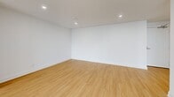 This well-designed 2-bedroom, 2-bathroom unit offers a thoughtfully laid-out single-floor plan with a clean, contemporary aesthetic throughout. Light-toned hardwood flooring flows seamlessly through the living spaces and bedrooms, complemented by crisp white walls and recessed lighting that create a bright, airy atmosphere.

The kitchen is a standout feature, showcasing light wood cabinetry extending to the ceiling, striking marble-veined quartz countertops and backsplash, stainless steel appliances including a dishwasher and range, and matte black hardware that adds a modern accent.

The living area is generously proportioned, bathed in natural light from large floor-to-ceiling windows that frame impressive city skyline views — a defining characteristic of this elevated unit.

The primary bedroom is spacious and includes a double-door closet, while the second bedroom offers a comfortable footprint with recessed lighting and direct access to the rest of the unit.

Both bathrooms are finished with the same design language: marble-look quartz vanity countertops, light wood cabinetry with open shelving, large-format floor tiles, and coordinating matte black fixtures and hardware. The primary bathroom also features an elegantly framed mirror and a tiled shower.

Overall, the unit presents a cohesive, modern design with high-quality finishes throughout.