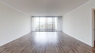Located at 2720 Neilson Way in Santa Monica, California, this single-floor residence offers an elevated living experience with sweeping panoramic views of the city and surrounding mountains. The open living area is a standout feature, anchored by a wall of floor-to-ceiling sliding glass doors that lead to a balcony, flooding the space with abundant natural light and framing breathtaking views of the Santa Monica skyline and beyond. Smooth hardwood-style flooring and crisp white walls throughout the living and bedroom areas create a clean, contemporary aesthetic.

The bedrooms continue the bright, airy theme, each featuring large sliding windows with city and mountain views, hardwood-style floors, and sheer drapery that softens incoming light. The entry foyer is finished with light tile flooring, providing a welcoming transition into the residence.

The kitchen is well-appointed with white cabinetry—including glass-front upper cabinets—warm-toned countertops, and tile flooring, offering ample storage and workspace. Two bathrooms serve the unit: one features a glass-enclosed walk-in shower and an extended vanity with generous counter space, while the second includes a combined shower and soaking tub with a sliding glass enclosure. Both bathrooms are finished with light tile flooring and bright, clean fixtures throughout.
