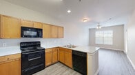 Located at 3500 Quail Creek Dr in Denton, TX, this one-bedroom, one-bathroom unit offers a well-organized single-floor layout with a functional and efficient use of space. The open-concept kitchen and living area form the heart of the unit, featuring warm honey-toned cabinetry, light speckled countertops, and a full suite of black appliances including a refrigerator, electric range, built-in microwave, and dishwasher. A peninsula counter with a stainless steel sink doubles as a pass-through, connecting the kitchen to the living area. The living room is finished with wood-style laminate flooring and receives natural light through a large window with blinds, complemented by a ceiling fan overhead. The bedroom is comfortably sized, finished with plush carpeting, and features a ceiling fan along with a window offering outdoor views. It connects conveniently to the bathroom, which includes a single-sink vanity with ample cabinetry, a large mirror, a tub-shower combination, and wood-style flooring. A walk-in closet adjacent to the bathroom provides generous storage. Two hallways and an additional closet further enhance storage and circulation throughout the unit.