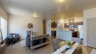 This single-story residence offers a thoughtfully designed open-concept layout that seamlessly connects the living, dining, and kitchen areas. The main living space features wood-look plank flooring, neutral-toned walls, and large windows dressed with vertical blinds that allow generous natural light to fill the room. The open layout provides a spacious, airy feel well-suited for both everyday living and entertaining.

The kitchen is a functional highlight, equipped with dark espresso-toned cabinetry, white countertops, and a full suite of stainless steel appliances including a range, microwave, dishwasher, and refrigerator. Pendant lighting over the kitchen peninsula adds warmth and definition to the space. A dedicated dining area sits adjacent, completing the open living zone.

The bedrooms are carpeted for comfort and each includes a closet with built-in shelving. One bedroom features a sliding window that brings in natural light. The full bathroom offers dark cabinetry with white countertops, a tub-shower combination, and wood-look flooring consistent with the rest of the unit.

A dedicated laundry room houses a full-size washer and dryer with overhead wire shelving for additional storage, adding practical convenience to the overall layout.