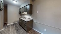 Located at 2704 Westmar Ct in Toledo, Ohio, this single-floor unit offers a straightforward, functional layout designed for comfortable everyday living. The kitchen features dark espresso-toned cabinetry with ample upper and lower storage, a double-basin stainless steel sink, dark laminate countertops, and durable wood-look vinyl plank flooring. A textured ceiling and under-cabinet lighting add practical detail to the space. The full bathroom is finished with wood-look vinyl plank flooring, a white vanity with cabinet storage, a full tub and shower combination, and a louvered bi-fold closet door providing additional storage. The living area is generously proportioned, featuring plush wall-to-wall carpeting, vertical blinds over a large window that invites natural light, and baseboard heating along the perimeter. Bedrooms continue the carpeted flooring and neutral toned walls, each equipped with louvered bi-fold closet doors offering built-in storage. One bedroom also includes a wall-mounted air conditioning unit for added climate control. Throughout the unit, a consistent neutral color palette, textured ceilings, and clean white trim create a cohesive and functional living environment.