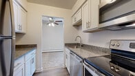 Located at 3303 Linden Rd in Rocky River, Ohio, this single-floor residence offers a well-designed layout that balances functionality and comfort. The galley-style kitchen is a standout feature, outfitted with stainless steel appliances including a range, built-in microwave, dishwasher, and full-size refrigerator. White shaker-style cabinetry with brushed nickel hardware lines both walls, complemented by granite countertops and a stainless steel sink with a modern gooseneck faucet. Wood-look luxury vinyl flooring runs throughout the kitchen, adding warmth and durability. The living area is generously proportioned, featuring neutral wall-to-wall carpeting, a textured ceiling, a ceiling fan, and large windows with vertical blinds that allow ample natural light. A sliding glass door provides access to an outdoor area. The bedroom is comfortably sized with soft carpeting and includes access to a walk-in closet with built-in shelving. The full bathroom is finished with wood-look vinyl flooring, a granite-topped vanity with white cabinetry, and a tiled tub-shower combination accented with classic decorative tile details. Baseboard heating is present throughout the unit, ensuring year-round comfort.