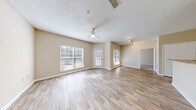 Located at 461 Old Dixie Way in Forest Park, Georgia, this single-floor, one-bedroom, one-bathroom residence offers a practical and comfortable layout designed for efficient everyday living. The open living room is bright and welcoming, featuring light-toned laminate wood flooring, a ceiling fan with light fixture, a textured ceiling, and multiple windows alongside a glass-paneled exterior door that flood the space with natural light and provide outdoor views. Track lighting adds an additional layer of ambiance to the living area. The kitchen is thoughtfully designed with a peninsula-style breakfast bar, white cabinetry, warm-toned countertops, a full suite of white appliances including a coil-top range and refrigerator, and wood-look flooring that ties seamlessly into the adjacent spaces. The spacious bedroom is carpeted for comfort, fitted with a ceiling fan, and features a large window allowing ample natural light. It includes direct access to both a walk-in closet with built-in shelving and the full bathroom. The bathroom is appointed with wood-look tile flooring, a single-sink vanity with a warm countertop, a wall mirror, and a tiled shower-tub combination. A hallway connects the main areas of the home, completing this well-organized and functional floor plan.