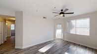 This single-floor residence offers a well-organized layout designed for comfortable everyday living. The main living area makes a strong first impression with durable wood-look flooring, crisp white walls, and a stylish ceiling fan with a built-in light fixture. Large windows dressed with blinds allow generous natural light to fill the space, while a glass-paneled exterior door provides convenient access to the outdoors.

The kitchen is thoughtfully appointed with white shaker-style cabinetry, neutral quartz-tone countertops, and a stainless steel sink set beneath a window overlooking the exterior. Stainless steel appliances — including a range, over-the-range microwave, and dishwasher — complete the functional and modern kitchen setup. The wood-look tile flooring carries through into this space, maintaining a cohesive aesthetic.

The bedrooms are carpeted for warmth and comfort, each featuring ceiling fans with lighting, windows with blinds that bring in natural light, and neutral wall tones that create a calm, inviting atmosphere. One bedroom benefits from a large walk-in closet outfitted with dual shelving rods and built-in shelves on both sides, offering ample storage capacity. Throughout the home, the clean, neutral palette and consistent design details provide a move-in-ready environment.