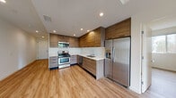 This contemporary single-floor unit offers a thoughtfully designed layout with modern finishes throughout. The kitchen is a standout feature, showcasing warm wood-tone cabinetry extending from floor to ceiling, white quartz countertops, and a full suite of stainless steel appliances including a gas range, built-in microwave, dishwasher, and a French door refrigerator with ice and water dispenser. Recessed lighting illuminates the space, highlighting the clean lines and functional design of the kitchen.

The living areas are bright and open, with light wood-look flooring that flows seamlessly throughout the unit, lending a warm and cohesive aesthetic. The spacious main living area features recessed lighting and clean white walls, providing a versatile canvas for any interior style. Additional rooms offer generous proportions, large closets with sliding doors, and natural light through well-placed windows.

Two bathrooms serve the unit. The primary bathroom features a glass-enclosed walk-in shower with tile surround, a wood-tone vanity with white countertop, and hardwood-style flooring. The secondary bathroom includes a full tub-shower combination, a matching vanity, and a large mirror. Clean, neutral finishes throughout both bathrooms contribute to the unit's modern and cohesive character.
