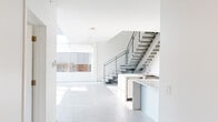 Located at 3300 Arbor Saline Rd in Ann Arbor, MI, this contemporary two-story home offers a thoughtfully designed layout across two well-proportioned floors. The main level makes an immediate impression with its crisp white palette, large-format tile flooring, and soaring open living area bathed in natural light through expansive floor-to-ceiling windows. A sleek, open-riser staircase with a metal railing serves as a striking architectural centerpiece, connecting the two floors with modern flair. A kitchen counter and sink are conveniently situated adjacent to the staircase on the main level.

The upper floor features an open hallway with a ceiling fan and large windows overlooking the exterior, providing a bright and airy transition between rooms. Five bedrooms offer generous accommodations, including a spacious primary suite complete with a walk-in closet outfitted with built-in shelving and hanging rods, as well as a private en-suite bathroom featuring a tiled corner soaking tub. Additional bedrooms are bright and well-sized, with large windows framing views of surrounding mature trees. Three full bathrooms serve the home throughout. The consistent use of neutral tile flooring, clean white walls, and modern fixtures throughout creates a cohesive, minimalist aesthetic from top to bottom.