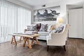 This single-story, 3-bedroom, 2-bathroom unit offers a practical and comfortable layout across a compact but efficiently utilized floor plan. The combined kitchen and living area serves as the heart of the home, where wood-look flooring flows throughout. The living room is bright and welcoming, highlighted by a large sliding glass door fitted with vertical blinds that allows generous natural light and provides direct access to an outdoor patio with green views. The kitchen is well-equipped with warm honey-toned wood cabinetry, granite-style countertops, a full suite of black appliances including a range, microwave, refrigerator, and dishwasher, plus a double stainless steel sink. The primary bedroom offers a comfortable footprint with carpeted flooring, a closet, and easy access to one of the two bathrooms. Both bathrooms feature a tub/shower combo, a vanity with ample counter space, a large mirror, and wood-look flooring. The additional bedrooms are served by a connecting hallway. A dedicated closet with built-in shelving and hanging rods provides practical storage. The overall layout is straightforward and functional, making efficient use of every square foot throughout the single-level floor plan.