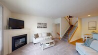 Located at 1 Applewood Drive in Perkasie, PA, this three-bedroom, three-bathroom townhouse offers comfortable living across three well-organized floors. The entry-level floor features a versatile secondary living area with plush carpeting and recessed lighting, ideal as a recreational or media room. The main floor serves as the heart of the home, showcasing a bright living room with a classic fireplace, large windows that invite natural light, and neutral carpeting. The kitchen is outfitted with warm honey-toned wood cabinetry, granite countertops, stainless steel appliances including a gas range, microwave, dishwasher, and refrigerator, plus easy-care hardwood-style flooring. A convenient half bathroom with a pedestal sink completes this level. The upper floor hosts all three bedrooms, including a generously sized primary bedroom with vaulted ceilings and a ceiling fan. A carpeted hallway connects the bedrooms to a full shared bathroom featuring a tub-shower combination with tile flooring. One of the secondary bedrooms features charming striped accent wallpaper and a closet. Throughout the home, clean neutral tones, soft carpeting in living and sleeping areas, and tasteful finishes create a warm, move-in-ready atmosphere.