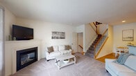Located at 1 Applewood Drive in Perkasie, PA, this three-bedroom, three-bathroom townhouse offers comfortable living across three well-organized floors. The entry-level floor features a versatile secondary living area with plush carpeting and recessed lighting, ideal as a recreational or media room. The main floor serves as the heart of the home, showcasing a bright living room with a classic fireplace, large windows that invite natural light, and neutral carpeting. The kitchen is outfitted with warm honey-toned wood cabinetry, granite countertops, stainless steel appliances including a gas range, microwave, dishwasher, and refrigerator, plus easy-care hardwood-style flooring. A convenient half bathroom with a pedestal sink completes this level. The upper floor hosts all three bedrooms, including a generously sized primary bedroom with vaulted ceilings and a ceiling fan. A carpeted hallway connects the bedrooms to a full shared bathroom featuring a tub-shower combination with tile flooring. One of the secondary bedrooms features charming striped accent wallpaper and a closet. Throughout the home, clean neutral tones, soft carpeting in living and sleeping areas, and tasteful finishes create a warm, move-in-ready atmosphere.