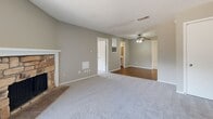 Located at 1111 Honeysuckle Way in Arlington, TX, this single-story, 3-bedroom, 3-bathroom home offers a well-organized layout across a comfortable footprint. The living room serves as the heart of the home, highlighted by a striking stone-surround fireplace, plush neutral carpet, and a sliding glass door that invites natural light and outdoor access. Ceiling fans are present throughout the living areas and bedrooms, ensuring year-round comfort. The galley-style kitchen is clean and functional, featuring white shaker cabinetry with modern hardware, light countertops, a double sink, and black appliances including a range, dishwasher, and refrigerator, all set atop warm hardwood-style flooring. A hallway with hardwood-style flooring connects the main living area to the private quarters. The primary bedroom is generously sized with soft carpet, a ceiling fan, and its own walk-in closet with built-in shelving on two walls. The additional bedrooms are carpeted and feature windows with natural light and ceiling fans. The bathrooms include tub-shower combinations with white tile surrounds. Textured ceilings are consistent throughout the home, adding a classic residential character to the overall design.