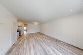 Located at 720 Eastview Drive in Central Islip, NY, this well-appointed 2-bedroom, 2-bathroom residence offers a thoughtfully designed single-level layout with a clean, modern aesthetic throughout. Light gray hardwood-style flooring flows seamlessly across the open-concept living and kitchen area, creating a cohesive and inviting atmosphere. Recessed lighting illuminates the spacious combined living and kitchen space, which is anchored by a sleek kitchen featuring white shaker cabinetry extending to the ceiling, white quartz countertops, a stainless steel undermount sink, and a full suite of stainless steel appliances including a gas range, built-in microwave, dishwasher, and French door refrigerator. The primary bedroom is generously sized, offering ample space for a full furniture arrangement. Both bedrooms feature large windows with views of the lush green surroundings, allowing abundant natural light to pour in. The two bathrooms are finished in a crisp, contemporary style with white vanities, undermount sinks, chrome fixtures, and tile flooring. Additional conveniences include three closets, a dedicated laundry area, and a utility room. The building exterior presents a classic colonial-style facade with well-maintained landscaping and open green lawns, contributing to a welcoming and peaceful residential setting.