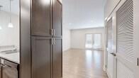 This single-story residence presents a clean, contemporary design characterized by a neutral color palette, light hardwood-style flooring in the main living areas, and plush carpeting in the bedrooms. The open-concept kitchen serves as a central highlight, showcasing rich dark espresso cabinetry with sleek bar-pull hardware, granite-look countertops, a peninsula with an undermount double sink, and black appliances including a refrigerator, range, and built-in microwave. Pendant lighting above the peninsula adds a modern touch, while a tiled backsplash provides visual contrast. Tall pantry-style cabinetry offers generous storage near the kitchen entry.

The living area is bright and open, illuminated by recessed lighting and anchored by French doors that allow natural light to filter in. Bedrooms are comfortably sized with carpeted floors, window blinds, and access to walk-in closets fitted with wire shelving systems. The primary bedroom connects directly to an en-suite bathroom, offering added privacy. Throughout the unit, crisp white trim, panel-style doors, and consistent neutral wall tones create a cohesive, move-in-ready ambiance.