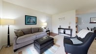Located at 397 Brixton Drive in Virginia Beach, Virginia, this single-floor home offers a cohesive coastal aesthetic throughout its well-appointed interior. The living room serves as a welcoming gathering space, featuring a combination of light carpet and hardwood-style flooring, neutral walls, and a large sliding glass door that fills the room with abundant natural light and provides outdoor views. The open layout comfortably accommodates seating and entertaining areas.

The galley-style kitchen is efficiently designed with warm wood cabinetry, dark granite-style countertops, a double sink, and a full range, with ample upper and lower cabinet storage. A dedicated laundry area is conveniently accessible from the kitchen.

Both bedrooms carry the home's signature coastal theme, featuring soft blue accent walls, plush carpeting, and natural light from well-placed windows. The rooms offer a calm, relaxed ambiance complemented by tasteful beach-inspired décor.

The two bathrooms are clean and functional, each featuring a tub-shower combination with tiled surrounds. One bathroom includes a wood-toned vanity with stone-style countertops and tile flooring, while the other offers convenient access to a walk-in closet area. Together, the spaces create a comfortable and inviting home with a consistent nautical charm throughout.