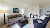 Located at 397 Brixton Drive in Virginia Beach, Virginia, this single-floor home offers a cohesive coastal aesthetic throughout its well-appointed interior. The living room serves as a welcoming gathering space, featuring a combination of light carpet and hardwood-style flooring, neutral walls, and a large sliding glass door that fills the room with abundant natural light and provides outdoor views. The open layout comfortably accommodates seating and entertaining areas.

The galley-style kitchen is efficiently designed with warm wood cabinetry, dark granite-style countertops, a double sink, and a full range, with ample upper and lower cabinet storage. A dedicated laundry area is conveniently accessible from the kitchen.

Both bedrooms carry the home's signature coastal theme, featuring soft blue accent walls, plush carpeting, and natural light from well-placed windows. The rooms offer a calm, relaxed ambiance complemented by tasteful beach-inspired décor.

The two bathrooms are clean and functional, each featuring a tub-shower combination with tiled surrounds. One bathroom includes a wood-toned vanity with stone-style countertops and tile flooring, while the other offers convenient access to a walk-in closet area. Together, the spaces create a comfortable and inviting home with a consistent nautical charm throughout.