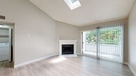 Located at 5324 S Broadway Cir in Englewood, CO, this efficiently designed one-bedroom, one-bathroom residence offers a thoughtful layout across a single floor. The living room is an immediate standout, featuring soaring vaulted ceilings, a skylight that floods the space with natural light, and a classic white-mantled fireplace. Light-toned luxury vinyl plank flooring runs throughout the main living areas, enhancing the bright, airy atmosphere. A sliding glass door opens to an outdoor balcony with lush greenery views, seamlessly connecting the interior to the outdoors. The galley-style kitchen is well-appointed with two-tone dark and white cabinetry, a hexagonal tile backsplash, stainless steel appliances including a range, microwave, and refrigerator, plus light countertops and track lighting overhead. The bedroom offers plush carpeting, a window with outdoor views, and convenient access to two closets. The full bathroom includes a dark-framed vanity mirror, white quartz countertop, dark cabinetry, and a tiled shower-tub combo. A dedicated in-unit laundry area houses a full-size washer and dryer with overhead shelving, adding practical convenience to this well-rounded residence.