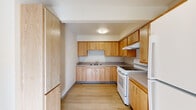 This single-floor unit offers a clean, functional layout designed with practicality and comfort in mind. A central hallway connects the main living areas, finished with light-toned wood-style flooring that runs through much of the unit, while plush carpet covers the bedroom spaces, adding warmth underfoot.

The kitchen is well-equipped with ample warm wood cabinetry that extends to the ceiling, offering generous storage throughout. A double-basin sink, a full-size electric range, refrigerator, and a tall pantry-style cabinet complete the space, which is finished with light wood flooring and neutral countertops.

The living area opens to the outdoors through a glass door flanked by a window, inviting natural light and providing outdoor views. Bedrooms are carpeted and feature closet space with bi-fold doors, neutral walls, and windows that bring in additional daylight.

The bathroom is thoughtfully designed with accessibility in mind, featuring stainless steel grab bars throughout, a tub with a built-in bench seat, and a curved shower rod. The overall palette of the unit is bright and neutral, with white walls and consistent trim details contributing to a clean, move-in-ready ambiance throughout.