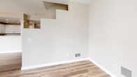 Located in the heart of downtown San Jose at 33 S 3rd St, this two-story residence offers a thoughtfully designed layout across two well-proportioned floors. The main level provides a welcoming open-plan living and dining area with light wood-look flooring, neutral tones, and large floor-to-ceiling windows dressed with vertical blinds that invite generous natural light. The kitchen is equipped with white cabinetry, dark granite countertops, a stainless steel sink, and modern stainless steel appliances including a range and over-the-range microwave. A convenient half bathroom is also found on this floor. The upper level hosts two comfortable bedrooms, each featuring plush carpeting, windows with city views, and easy access to the private balcony through expansive glazed doors with vertical blinds. The spacious primary bedroom includes a generous walk-in closet with wire shelving systems offering ample storage. Two full bathrooms serve the upper level, each finished with wood-look tile flooring, white vanities, and clean, contemporary fixtures — one featuring a soaking tub. With five closets total across the home, storage is plentiful. The residence offers a bright, clean aesthetic and a functional two-floor flow ideal for modern urban living.
