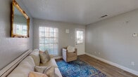 This single-floor residence offers a thoughtfully designed layout that maximizes comfort and functionality. The living area serves as the heart of the home, featuring warm wood-look flooring, neutral gray walls, and a textured ceiling. Natural light streams in through large windows fitted with horizontal blinds, creating a bright and welcoming atmosphere. A decorative gold-framed mirror adds an elegant accent to the space.

The kitchen is clean and modern, showcasing white shaker-style cabinetry, granite countertops, a white subway tile backsplash, and black appliances including a range, microwave, and refrigerator. The wood-look flooring continues seamlessly from the living areas into the kitchen.

A dedicated dining area provides a functional space for meals, complete with overhead lighting and neutral walls that keep the area feeling open and airy.

The bedrooms are serene retreats, each featuring wood-look flooring, neutral tones, and ceiling fans to ensure comfort. Natural light filters through windows with blinds, and ample space accommodates full furniture arrangements.

The bathroom is crisp and clean, featuring a granite-topped vanity with white cabinetry, a tub-shower combination with white tile surround, and wood-look flooring that ties the space together cohesively. Throughout, the residence presents a consistent, neutral palette that is both inviting and move-in ready.