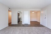 Located on Hidden Glen Drive SE in Marietta, Georgia, this single-floor unit offers a practical and functional layout across several distinct spaces. The living room serves as the central gathering area, finished with wall-to-wall carpet and a textured ceiling. A full-width sliding glass door fitted with vertical blinds opens to a private balcony, allowing natural light to fill the room and providing views of surrounding greenery.

Adjacent to the living area, a dining space features wood-look flooring that transitions seamlessly into the kitchen. The kitchen is equipped with rich, dark wood cabinetry — both upper and lower — paired with light granite-style countertops. A double-basin sink, dishwasher, and range provide full functionality, while wood-look flooring ties the space together.

The bedroom is generously sized, featuring soft carpet underfoot, a textured ceiling, and a window that admits natural light. A closet provides dedicated storage within the room.

The bathroom includes a full tub-and-shower combination with white tile surround, a toilet, and a vanity with dark cabinetry and a white countertop. Wood-look flooring extends throughout the bathroom, maintaining a consistent aesthetic across the unit's hard-surface areas.