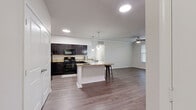 This single-floor residence is designed with an open-concept layout that seamlessly connects the kitchen and living areas, creating a spacious and cohesive environment. The kitchen is well-equipped with dark espresso cabinetry, granite-style countertops, and a full suite of black appliances, including a range, microwave, and refrigerator. A central island with pendant lighting above provides additional prep space and casual seating, while recessed lighting ensures the area is well-lit throughout.

The living area extends naturally from the kitchen, featuring crown molding, a ceiling fan, and access to an exterior door flanked by windows that invite natural light. Wood-style flooring runs consistently throughout the home, lending a cohesive and contemporary aesthetic to each room.

The bedrooms are well-proportioned, each featuring ceiling fans, multiple windows with blinds, and the same durable wood-style flooring. The primary bedroom connects to a spacious bathroom with a dual-sink vanity topped with granite-style counters, dark cabinetry, and a soaking tub. An adjoining walk-in closet offers extensive wire shelving and hanging space. A secondary bathroom mirrors the design with a single-sink vanity and tub-shower combination.