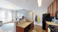 Located at 3009 M E Valentine Dr in Raleigh, NC, this single-floor unit offers a functional and well-organized layout designed for comfortable living. The kitchen is a standout feature, equipped with warm wood-toned cabinetry extending to the ceiling for ample storage, black appliances including a refrigerator, range, and microwave, and a peninsula countertop that opens directly to the living area. Wood-style flooring runs through the kitchen and common spaces, adding warmth and continuity throughout. The open-concept design connects the kitchen seamlessly to the living room, creating an inviting shared space with vaulted ceiling details that lend a sense of added volume. Multiple bedrooms are carpeted and bright, each featuring windows that allow natural light to fill the rooms. The bedrooms vary in size and offer closet access, providing practical storage solutions. Two bathrooms serve the unit, each finished with tile flooring, wood-toned vanity cabinetry, and well-lit mirrors. The overall design is clean and neutral, with white walls throughout that create a bright, open atmosphere. This unit presents a practical and comfortable floor plan well-suited for everyday living in Raleigh.