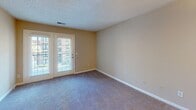 Located at 34 Woodcross Dr in Columbia, SC, this single-floor residence offers a well-designed layout that balances comfort and functionality. The kitchen is a standout feature, showcasing gray shaker-style cabinetry, granite countertops, a bold dark subway tile backsplash, and stainless steel appliances including a range, microwave, and refrigerator. Wood-look flooring grounds the kitchen space with a clean, modern aesthetic. Adjacent to the kitchen, the dining area is defined by a stylish pendant light and plush carpeting, creating a warm and inviting atmosphere. The spacious living room features French doors that invite natural light and provide views of the surrounding area, with soft carpet underfoot. The bedrooms are generously proportioned, each with plush carpeting and large windows fitted with blinds that allow for natural light control. One bedroom includes a walk-in closet with built-in shelving and hanging rods for ample storage. The bathroom is thoughtfully appointed with wood-look flooring, a soaking tub and shower combination, and a vanity, providing a clean and functional space. Throughout the unit, neutral warm-toned walls and textured ceilings contribute to a cohesive and comfortable living environment.