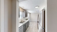 This single-floor residence in Lexington, Kentucky offers a thoughtfully designed layout across two bedrooms and one full bathroom. The interior presents a neutral, contemporary palette throughout, with warm beige walls and clean white trim providing a cohesive aesthetic from room to room.

The kitchen is a standout feature, showcasing gray cabinetry with brushed nickel hardware, light quartz-style countertops, a double-basin sink, and stainless steel appliances including a dishwasher and refrigerator. Light wood-look luxury vinyl flooring runs through the kitchen and flows into the adjacent dining area, which benefits from natural light through horizontal blinds. Flush-mount ceiling fixtures provide consistent overhead lighting.

The spacious living room features the same durable vinyl flooring and is highlighted by a full-width sliding glass door that opens to an outdoor area, filling the space with natural light and outdoor views.

Both bedrooms are carpeted and generously sized, each with large windows fitted with blinds. One bedroom features a single closet, while the other offers the added convenience of a double bi-fold closet configuration, providing ample storage.

The full bathroom is finished with gray cabinetry, a single-sink vanity with a light countertop, wood-look flooring, and a tiled tub-shower combination, completing this well-maintained home.