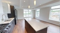 Unit 508 is a thoughtfully designed 1-bedroom, 1-bathroom residence that blends modern aesthetics with functional living. The open-concept layout seamlessly connects the kitchen and living areas, creating a bright and airy atmosphere throughout.

The kitchen is a standout feature, boasting a large center island with a sleek quartz countertop and rich, dark cabinetry that provides ample storage. Stainless steel appliances complete the space, offering both style and practicality. Pendant lighting above the island adds a refined touch, while recessed lighting throughout ensures a well-lit environment.

The living area benefits from an abundance of natural light, courtesy of a generous arrangement of large windows that frame pleasant outdoor views of the surrounding neighborhood. The tray ceiling adds architectural interest and a sense of elevated space. Warm-toned hardwood flooring runs throughout, grounding the clean, neutral color palette and lending the unit a welcoming, cohesive feel.

Overall, the unit presents a crisp, contemporary interior with quality finishes and a layout that maximizes comfort and livability — ideal for those seeking a refined and low-maintenance living experience.