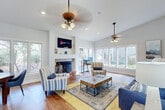 Located at 27670 US-98 W in Daphne, Alabama, this single-floor property offers a thoughtfully designed layout that blends comfort and functionality. The main living area is the centerpiece of the space, characterized by soaring ceilings, warm hardwood flooring, and an abundance of natural light streaming through a generous array of windows along multiple walls. A tiled fireplace with a built-in mantle serves as an architectural focal point, complemented by a wall-mounted television above it. Dual ceiling fans enhance the airy atmosphere throughout the room.

The living area flows seamlessly into a versatile workspace nook, positioned beside a large bank of windows overlooking the surrounding greenery — ideal for a home office setup. A separate seating area with direct access to the outdoors via French doors provides an inviting transition to the exterior.

The entry foyer features tile flooring, vaulted ceilings with track lighting, and a set of French doors flanked by transom windows that bathe the space in natural light. A hallway connects the main living area to additional rooms, with tall ceilings continuing throughout, reinforcing the open, expansive feel of the home. The overall ambiance is bright, welcoming, and well-suited for both everyday living and entertaining.