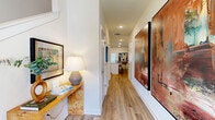 Located in Sugar Hill, Georgia, this two-story home offers a well-designed layout spread across two balanced floors. The main level features an open-concept kitchen and living area anchored by light hardwood-style flooring throughout. The kitchen is outfitted with white shaker cabinetry, granite countertops, stainless steel appliances including a gas range and built-in microwave, and a central island with seating — ideal for both cooking and casual dining. A dedicated pantry adds practical storage, while natural light filters in through large windows dressed with shutters. The living room features warm, neutral tones, with windows overlooking lush greenery and a welcoming layout. A hallway adorned with recessed lighting connects the main living spaces.

Upstairs, the spacious primary bedroom includes plush carpeting, a ceiling fan, and direct access to both a private bathroom and a walk-in closet. The second bedroom is equally well-proportioned with carpet flooring and closet access. All three bathrooms are finished with granite countertops, white cabinetry, and tile surrounds in the tub-shower combinations. The home maintains a clean, contemporary aesthetic throughout, with consistent finishes and a bright, airy ambiance that carries from room to room.